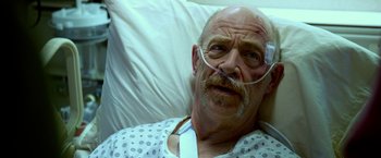 Movie still from “Father Figures” (2017), directed by Lawrence Sher – An older man in a hospital bed wearing a white and black polka dot shirt; Close Up shot, High angle