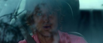 Movie still from “Father Figures” (2017), directed by Lawrence Sher – A man with long hair and a pink shirt is in a car; Close Up shot, Over the shoulder angle