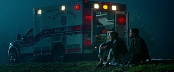 Movie still from “Father Figures” (2017), directed by Lawrence Sher – A man sitting in front of an ambulance at night; Wide shot, Low angle