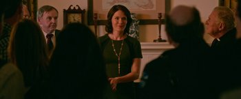 Movie still from “Father Figures” (2017), directed by Lawrence Sher – A woman standing in front of a group of people; Medium shot, Over the shoulder angle