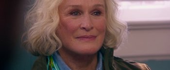 Movie still from “Father Figures” (2017), directed by Lawrence Sher – An older woman with blonde curly hair wearing a blue shirt; Close Up shot, Over the shoulder angle