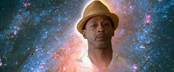 Movie still from “Father Figures” (2017), directed by Lawrence Sher – A man wearing a straw hat in front of a space background; Close Up shot, Low angle