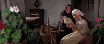 Movie still from “Fiddler on the Roof” (1971), directed by Norman Jewison – A woman is knitting a hat while another woman looks on; Medium shot, High angle