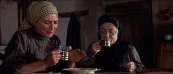 Movie still from “Fiddler on the Roof” (1971), directed by Norman Jewison – Two women are sitting at a table and drinking tea; Medium shot, Low angle