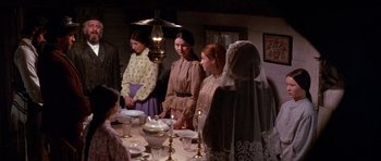 Movie still from “Fiddler on the Roof” (1971), directed by Norman Jewison – A group of people standing around a table with candles; Medium shot, High angle