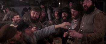 Movie still from “Fiddler on the Roof” (1971), directed by Norman Jewison – A group of men in hats are drinking from cups; Medium shot, Overhead angle