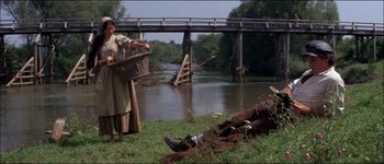 Movie still from “Fiddler on the Roof” (1971), directed by Norman Jewison – A woman standing next to a body of water; Wide shot, High angle