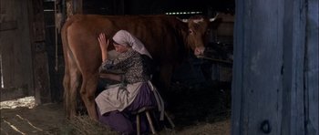 Movie still from “Fiddler on the Roof” (1971), directed by Norman Jewison – A woman milking a cow in a barn; Wide shot, High angle