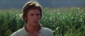 Movie still from “Fiddler on the Roof” (1971), directed by Norman Jewison – A man in a white shirt standing next to a field of corn; Close Up shot, Over the shoulder angle