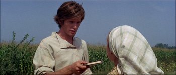 Movie still from “Fiddler on the Roof” (1971), directed by Norman Jewison – A man holding a book in front of a woman in front of a cornfield; Close Up shot, Over the shoulder angle