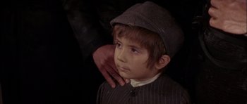 Movie still from “Fiddler on the Roof” (1971), directed by Norman Jewison – A young boy wearing a hat with a hand on his shoulder; Close Up shot, High angle