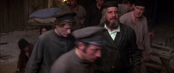 Movie still from “Fiddler on the Roof” (1971), directed by Norman Jewison – A group of men standing next to each other in a room; Medium shot, Low angle