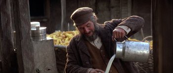 Movie still from “Fiddler on the Roof” (1971), directed by Norman Jewison – An old man in a brown coat and a brown hat is looking at something; Medium shot, High angle