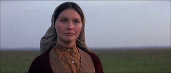 Movie still from “Fiddler on the Roof” (1971), directed by Norman Jewison – A woman with a head scarf standing in a field; Close Up shot, Low angle
