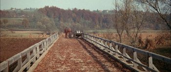 Movie still from “Fiddler on the Roof” (1971), directed by Norman Jewison – Two people standing on a bridge over a river; Extreme Wide shot, High angle