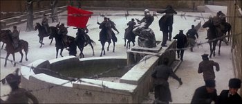 Movie still from “Fiddler on the Roof” (1971), directed by Norman Jewison – A group of people on horses are riding in the middle of the street; Wide shot, High angle