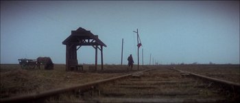 Movie still from “Fiddler on the Roof” (1971), directed by Norman Jewison – A person walking on a train track near a wooden structure; Extreme Wide shot, Low angle