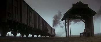 Movie still from “Fiddler on the Roof” (1971), directed by Norman Jewison – A train traveling down train tracks next to a building; Extreme Wide shot, Low angle