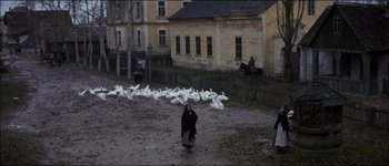 Movie still from “Fiddler on the Roof” (1971), directed by Norman Jewison – A group of people standing next to a flock of birds; Wide shot, High angle