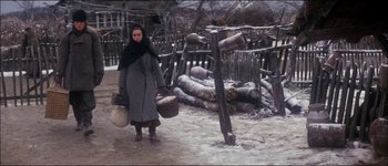 Movie still from “Fiddler on the Roof” (1971), directed by Norman Jewison – A woman in a gray coat holding two baskets; Wide shot, High angle