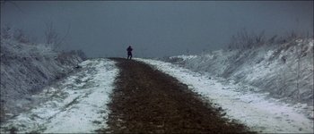 Movie still from “Fiddler on the Roof” (1971), directed by Norman Jewison – A person on a dirt road in the middle of a snowy field; Extreme Wide shot, High angle