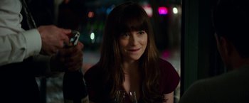 Movie still from “Fifty Shades Darker” (2017), directed by James Foley – A beautiful woman holding a wine glass and a bottle; Close Up shot, Over the shoulder angle