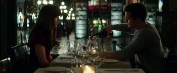 Movie still from “Fifty Shades Darker” (2017), directed by James Foley – A person pouring a glass of wine at a table; Medium shot, Over the shoulder angle
