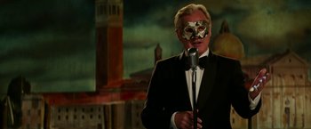 Movie still from “Fifty Shades Darker” (2017), directed by James Foley – A man wearing a mask and holding a microphone; Medium shot, Low angle