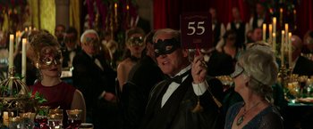 Movie still from “Fifty Shades Darker” (2017), directed by James Foley – A man in a tuxedo holding up a 5 5 sign; Medium shot, Over the shoulder angle