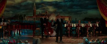 Movie still from “Fifty Shades Darker” (2017), directed by James Foley – A group of men in suits performing on a stage; Wide shot, High angle