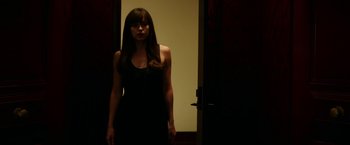 Movie still from “Fifty Shades Darker” (2017), directed by James Foley – A woman standing in front of a door in a dark room; Medium shot, Over the shoulder angle