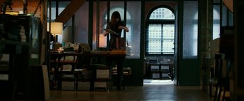 Movie still from “Fifty Shades Darker” (2017), directed by James Foley – A woman standing in front of stacks of books in a room; Wide shot, High angle