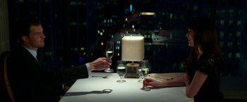 Movie still from “Fifty Shades Darker” (2017), directed by James Foley – Two people are holding wine glasses at a dinner table; Medium shot, High angle