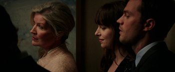 Movie still from “Fifty Shades Darker” (2017), directed by James Foley – A woman standing next to a man and a woman; Close Up shot, Over the shoulder angle