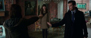 Movie still from “Fifty Shades Darker” (2017), directed by James Foley – A group of people in a room talking to a woman in a brown coat; Medium shot, Over the shoulder angle