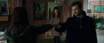 Movie still from “Fifty Shades Darker” (2017), directed by James Foley – A man and a woman holding hands in front of another man; Medium shot, Over the shoulder angle