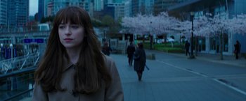 Movie still from “Fifty Shades Darker” (2017), directed by James Foley – A woman is walking down the sidewalk in the city; Medium shot, Over the shoulder angle