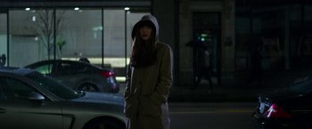 Movie still from “Fifty Shades Darker” (2017), directed by James Foley – A woman wearing a coat and a hood on a city street; Wide shot, High angle