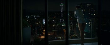 Movie still from “Fifty Shades Darker” (2017), directed by James Foley – A man standing on a window ledge looking out at a city at night; Extreme Wide shot, High angle