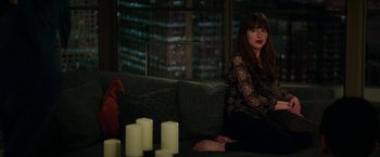 Movie still from “Fifty Shades Darker” (2017), directed by James Foley – A woman sitting on a couch in front of candles; Wide shot, High angle