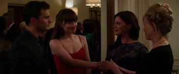 Movie still from “Fifty Shades Darker” (2017), directed by James Foley – Two women are shaking hands at a party; Medium shot, Over the shoulder angle