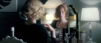 Movie still from “Filth” (2013), directed by Jon S. Baird – A woman looking in the mirror in front of a mirror; Close Up shot, Over the shoulder angle
