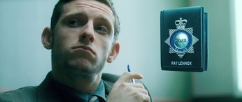 Movie still from “Filth” (2013), directed by Jon S. Baird – A person holding a pen; Close Up shot, Low angle
