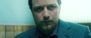 Movie still from “Filth” (2013), directed by Jon S. Baird – A person wearing a suit and tie; Close Up shot, Low angle