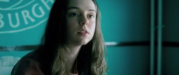 A young woman with long hair is looking at the camera