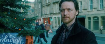 Movie still from “Filth” (2013), directed by Jon S. Baird – A person wearing a suit and tie; Close Up shot, Over the shoulder angle