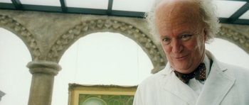 Movie still from “Filth” (2013), directed by Jon S. Baird – An older man in a white lab coat; Close Up shot, Low angle