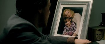 Movie still from “Filth” (2013), directed by Jon S. Baird – A man sitting in front of a picture of a woman and a child; Extreme Close Up shot, Over the shoulder angle