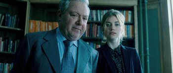 Movie still from “Filth” (2013), directed by Jon S. Baird – A man and a woman standing next to each other in front of a bookcase; Close Up shot, Low angle