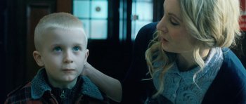 Movie still from “Filth” (2013), directed by Jon S. Baird – A young boy and a young woman sitting in front of a window; Close Up shot, Over the shoulder angle